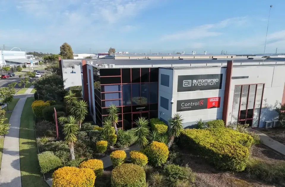 Automated Innovation's premises at 1/12 Channel Rd, Mayfield West: a two-storey grey building with a dark glass front and landscaped gardens