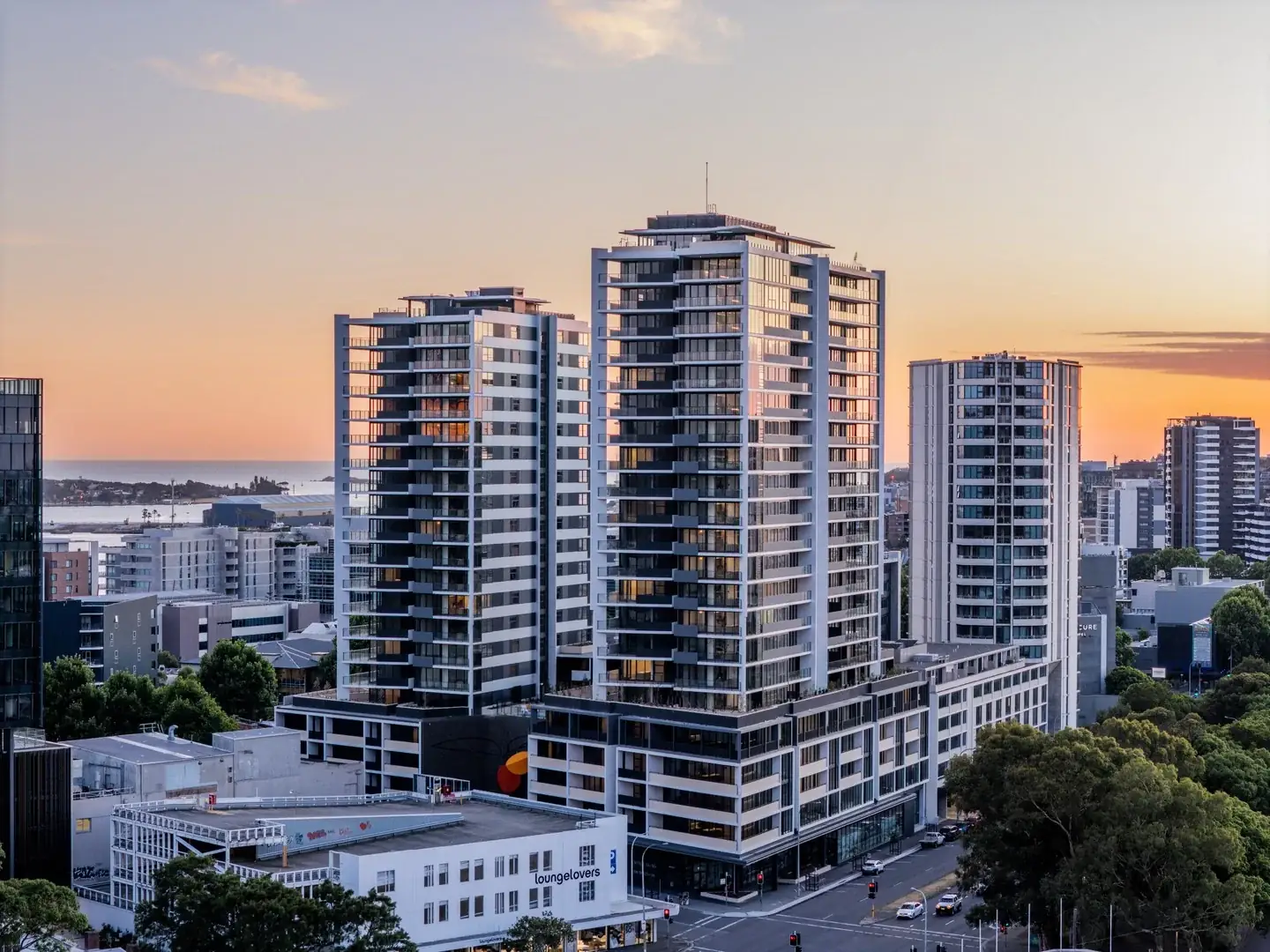 ONE Apartments, Newcastle: residential towers at dusk with the harbour behind